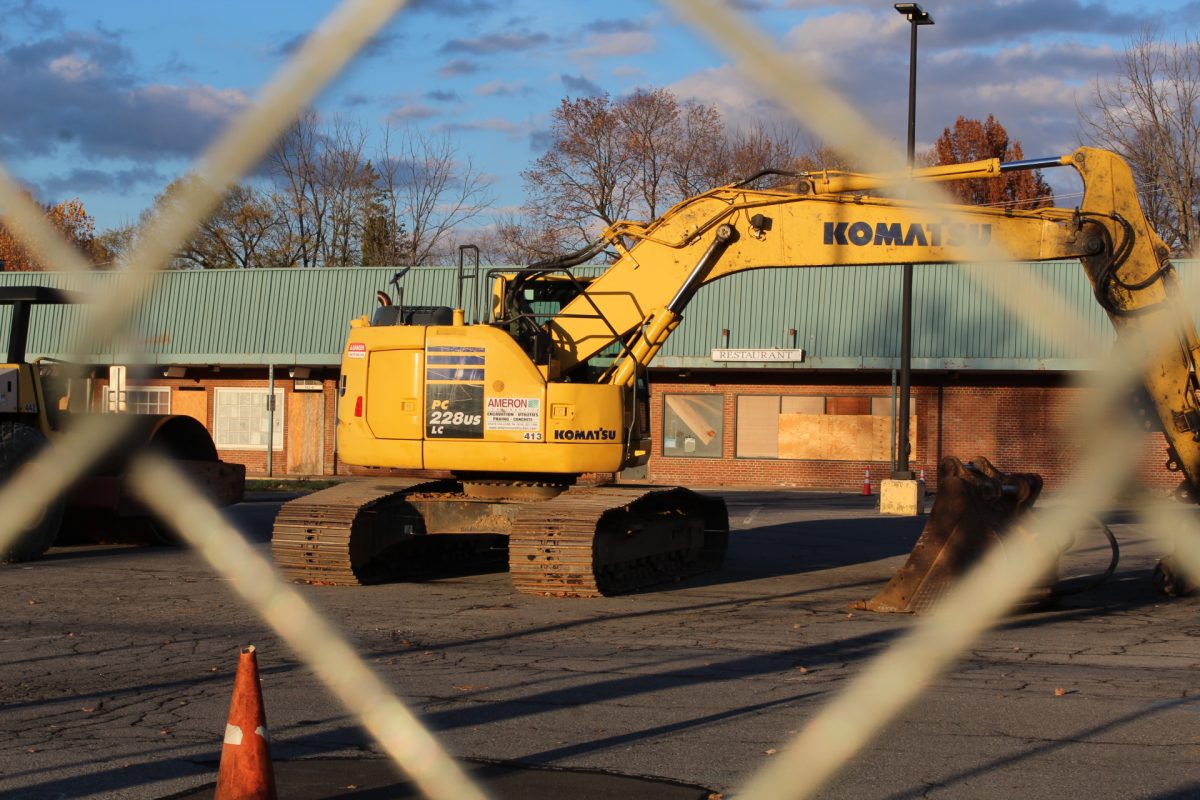 Looking through the fence blocking off the east side of Westerly Parkway Plaza at an excavator.