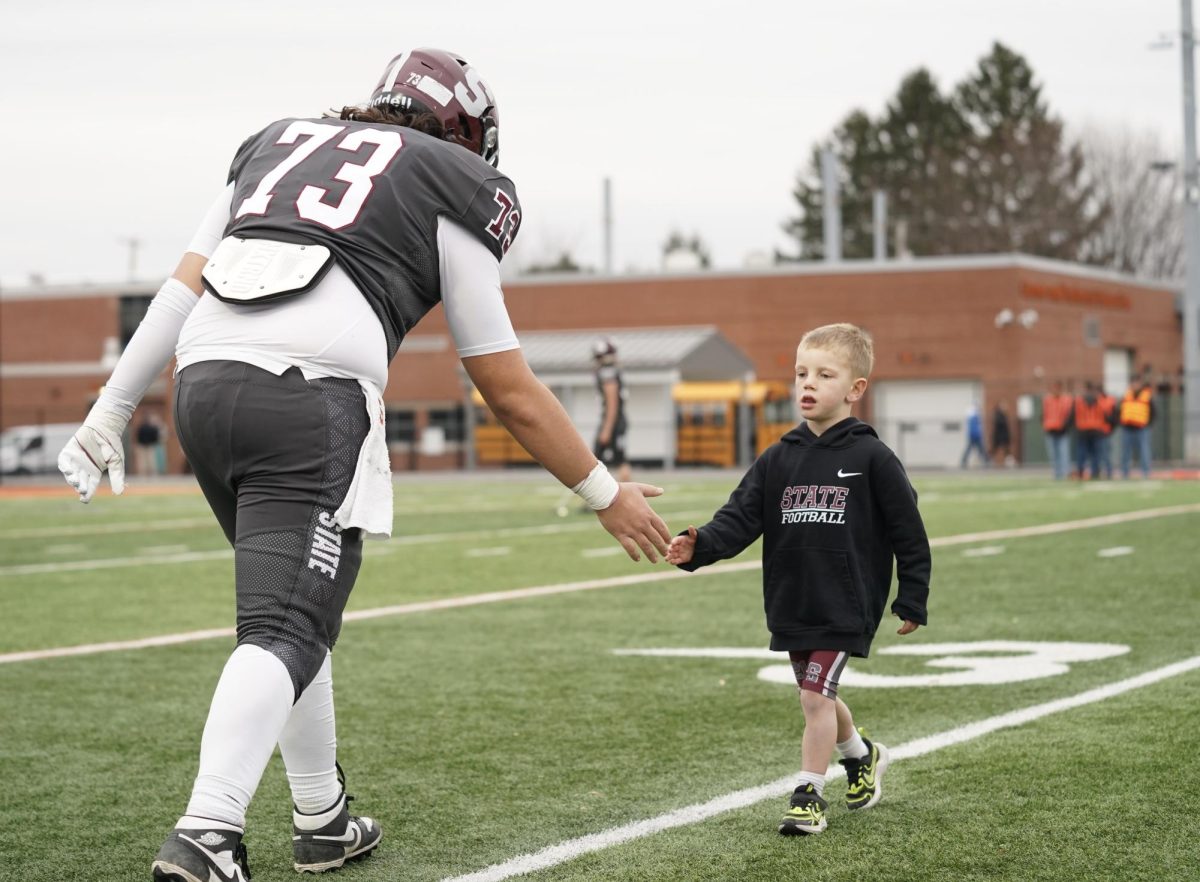 Senior captain Luke Milito high fives the son of one of his coaches as the two go through warm-ups together.