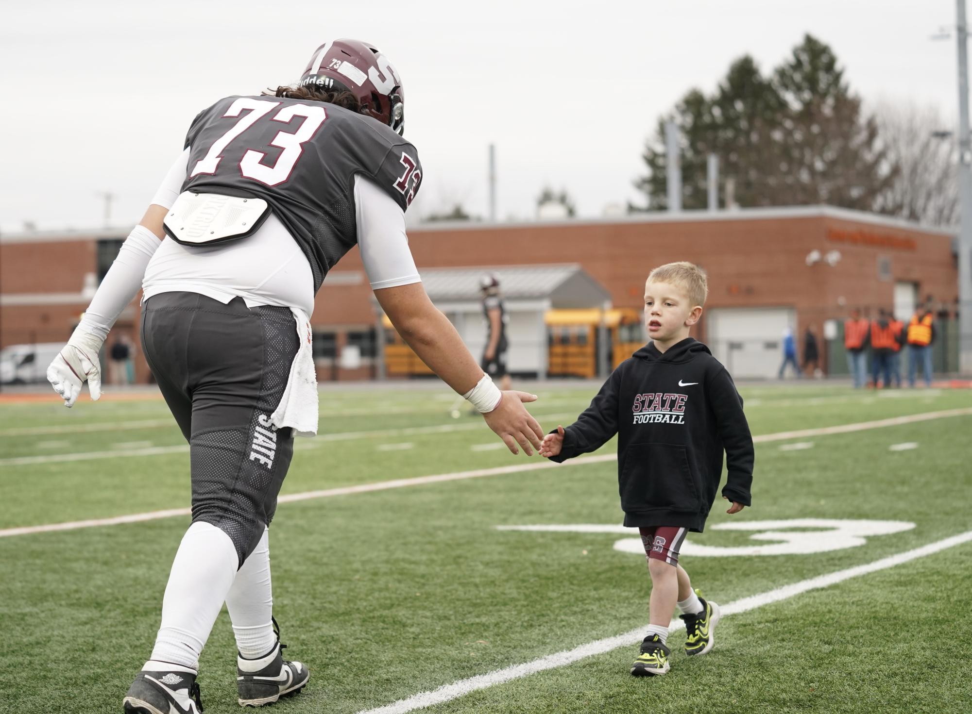 Senior captain Luke Milito high fives the son of one of his coaches as the two go through warm-ups together.