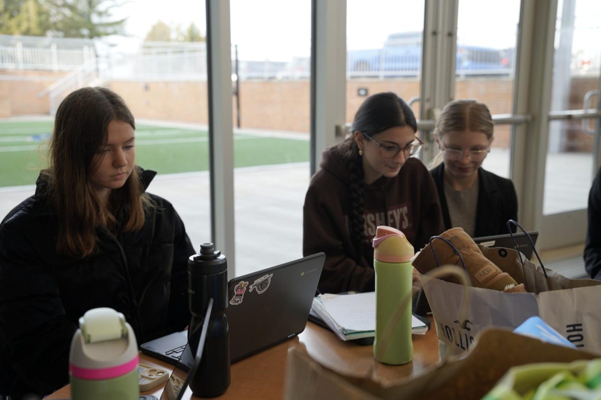 Sophomores Ellie Embser and Emily Brightbill, along with Junior Quinn Hixson, sit at a table preparing for the first Public Forum debate round.