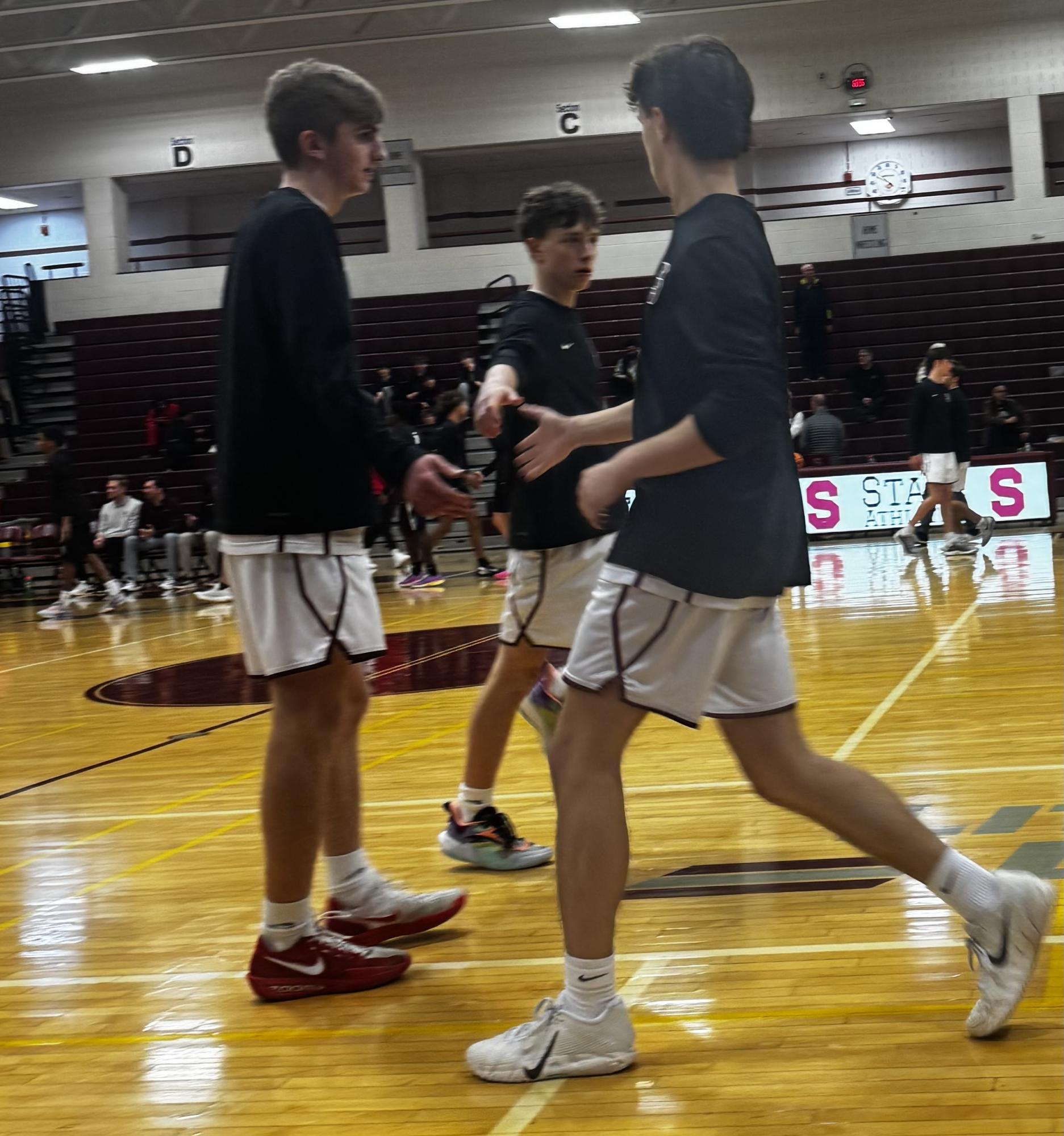 Senior Michael Powell high fives senior Parker Thurley and junior JJ Powell during warmups