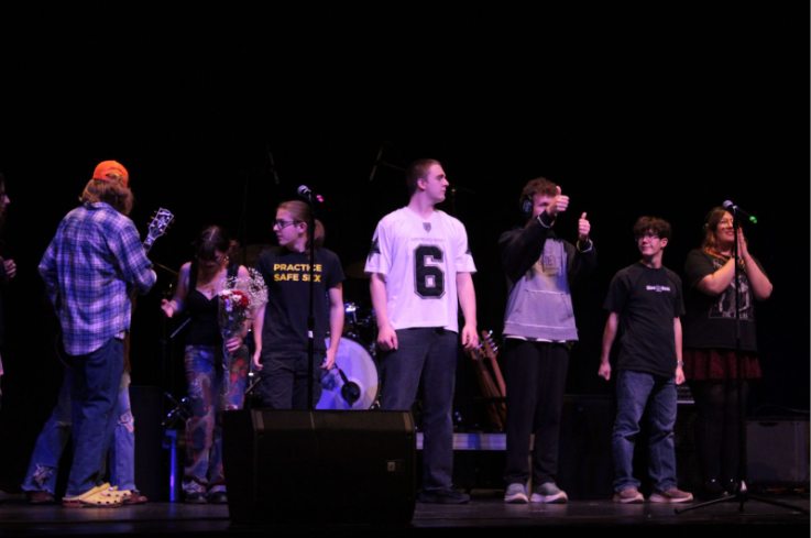 Rock band crew posing for their photo and gathering the rest of the musicians.