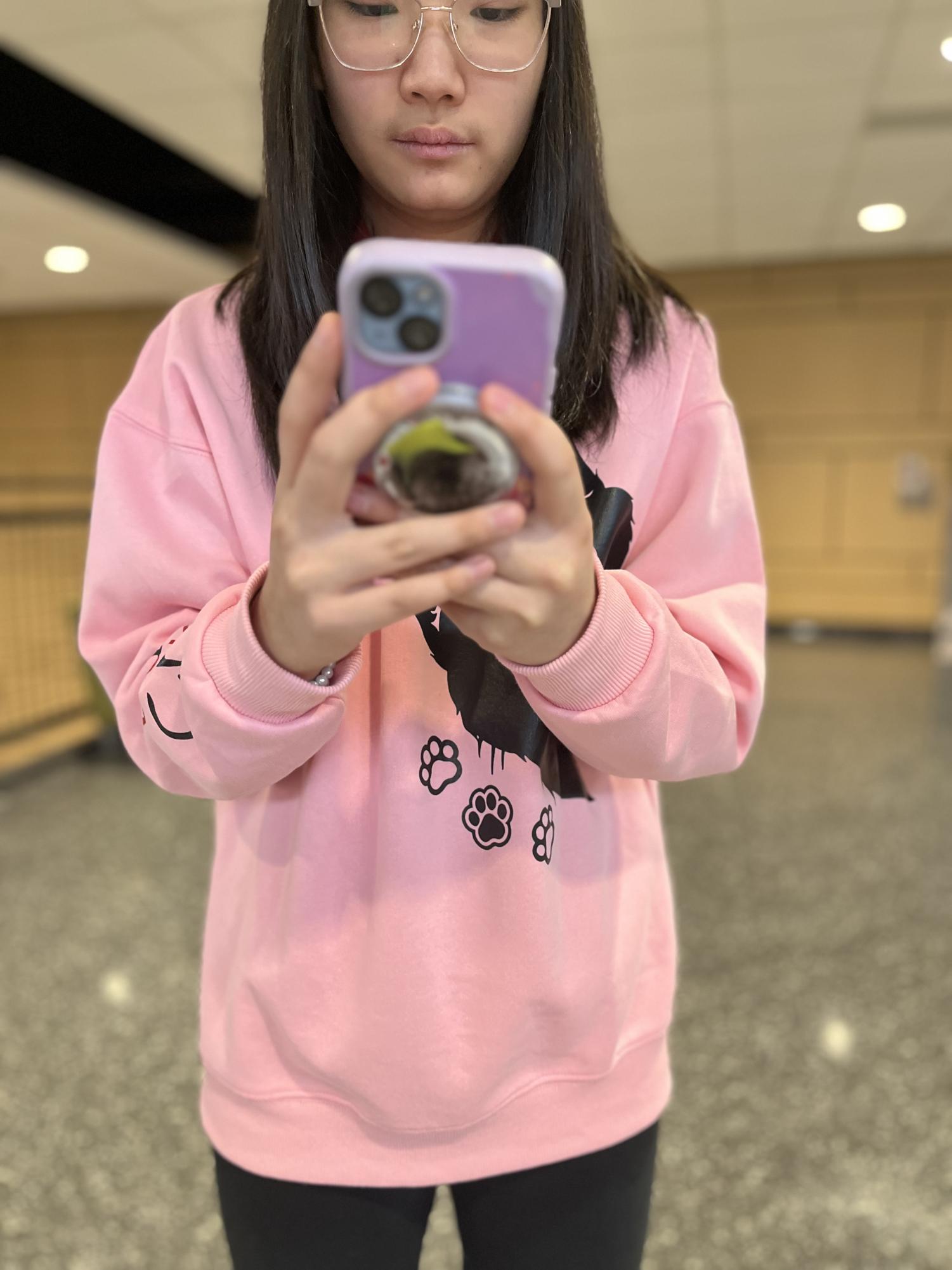 Kylie Matsueda poses for a photo while using her phone during the school day. 

