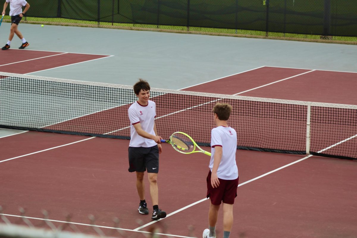Senior Dash Nealon taps rackets with teammate freshman Henry Poole in celebration of winning their set in a game against Palmyra High School on March 26.