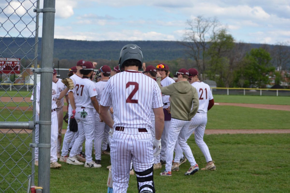 Senior Max Herncane watches the team huddle up in the middle of the second inning. “I would say that this team is full of fighters, we don’t quit, and everyone has each other’s backs so we fight through everything together,” Herncane said. 